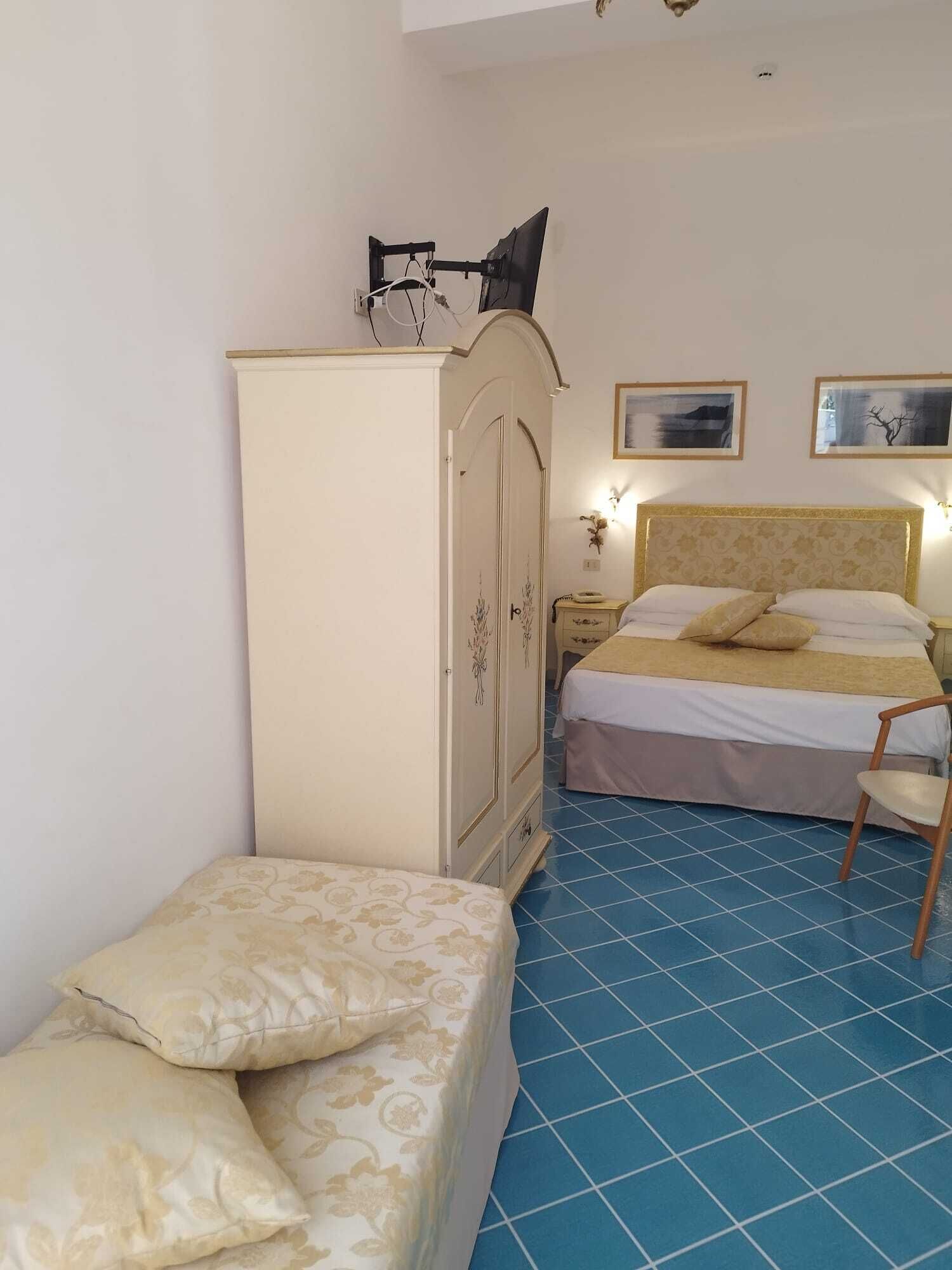 A bedroom with a bed, a wardrobe, a nightstand, and a chair.