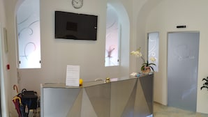 Un mostrador de recepción con un reloj, un florero con flores y una pizarra con notas.
