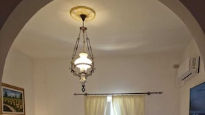 Una habitación de hotel con una cama, un escritorio, una silla, una lámpara de escritorio, un aire acondicionado de pared y un cuadro en la pared.