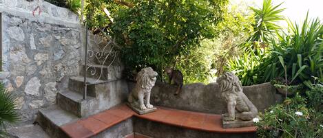 A stone wall with a metal spiral staircase and two stone lion statues.