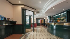 A hotel lobby with a check-in counter, a reception desk, and a patterned floor. - Hotel Montreal (Ragusa)