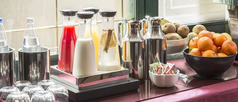 A buffet setup with various beverages and fruits.