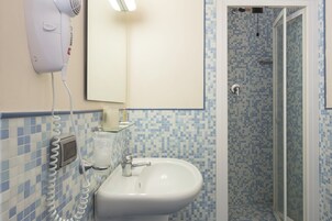 Un bagno con un lavandino bianco, un asciugacapelli e una doccia con piastrelle di mosaico blu.