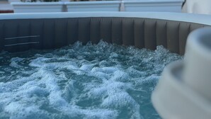 A hot tub with water bubbling, surrounded by a modern building with a flat roof and some greenery. - Hotel Montreal (Ragusa)