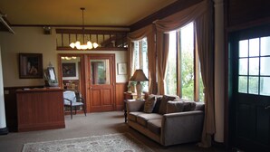 A cozy living room with a sofa, a coffee table, a rug, and a dining area with a chair and table. - Hotel Halsingland (Haines)