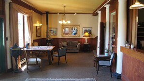 A traditional living room with a dining area, featuring a chandelier, a fireplace, and a large mirror. - Hotel Halsingland (Haines)