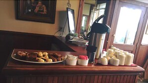 A breakfast bar with a plate of pastries, a coffee maker, and several containers of cream. - Hotel Halsingland (Haines)