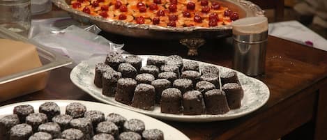 Ett bord med olika sorters efterrätter, inklusive en paj med körsbär, ett fat med brownies och en tallrik med chokladöverdragna godsaker.