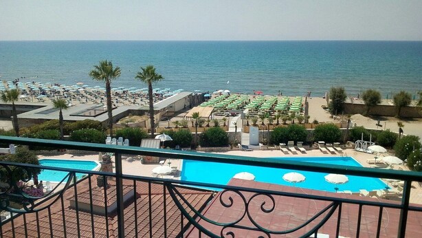 Un espace piscine avec vue sur la mer, agrémenté de parasols et de chaises longues.
