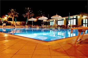 Una piscina al aire libre de temporada, sombrillas