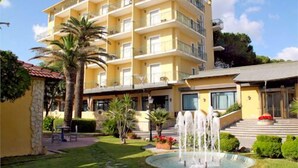 Un hôtel à plusieurs étages doté de balcons, d’une cour intérieure avec une fontaine et d’un espace piscine.