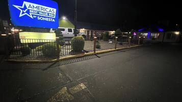A nighttime view of a hotel with a prominent sign reading "AMERICAS BEST VALUE INN BY SONESTA".