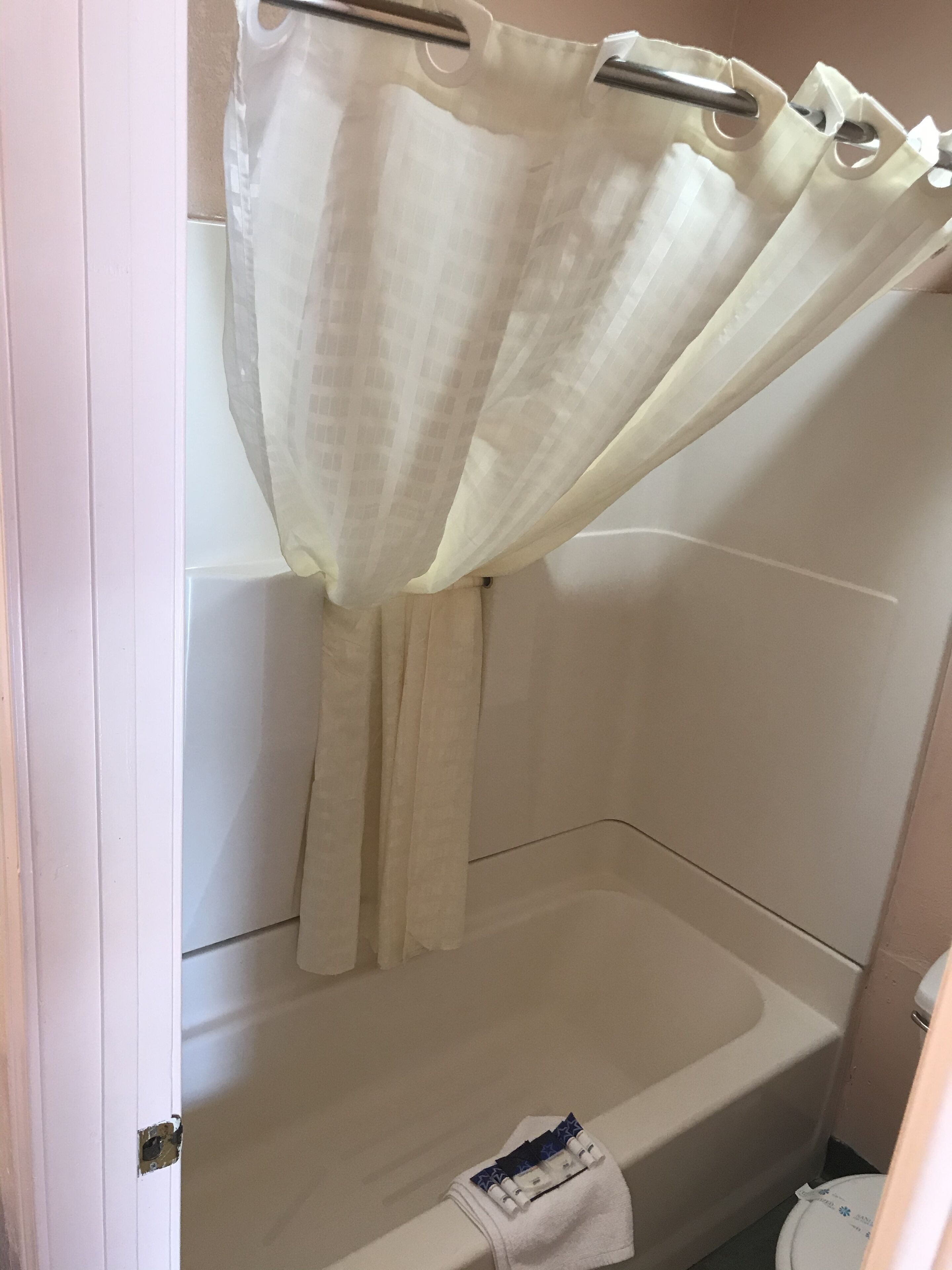 Een badkamer met douchegordijn, bad en handdoekhouder.