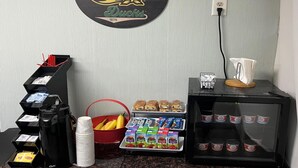 Eine Wand mit einem kreisförmigen Oregon Ducks Logo, einer Kaffeemaschine, einer Obstschale, einer Snackauslage und einem Taschentuchhalter.