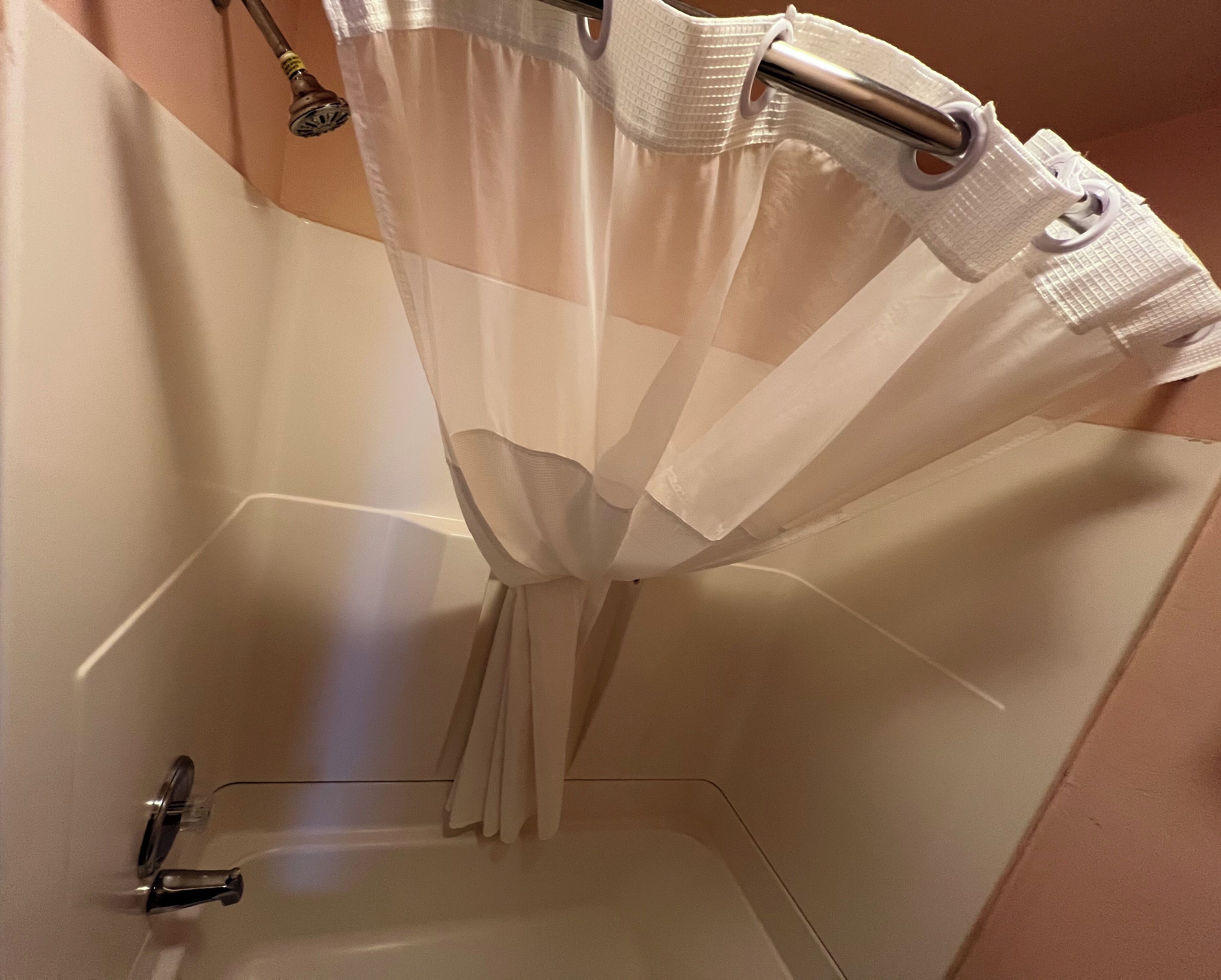 A bathroom with a bathtub, a shower curtain, and a towel rack.