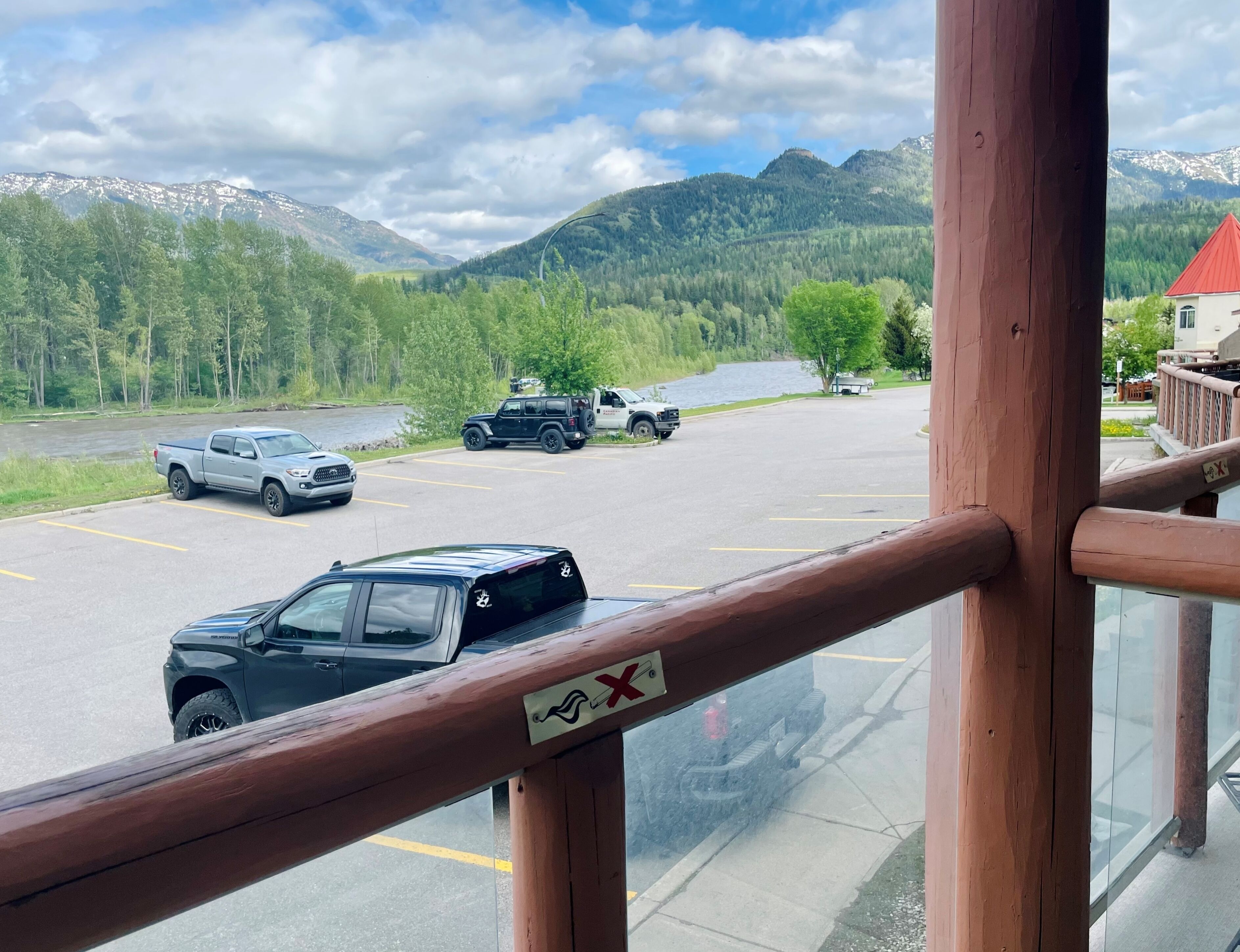 A parking area with vehicles, a view of a lake, and mountains in the background.