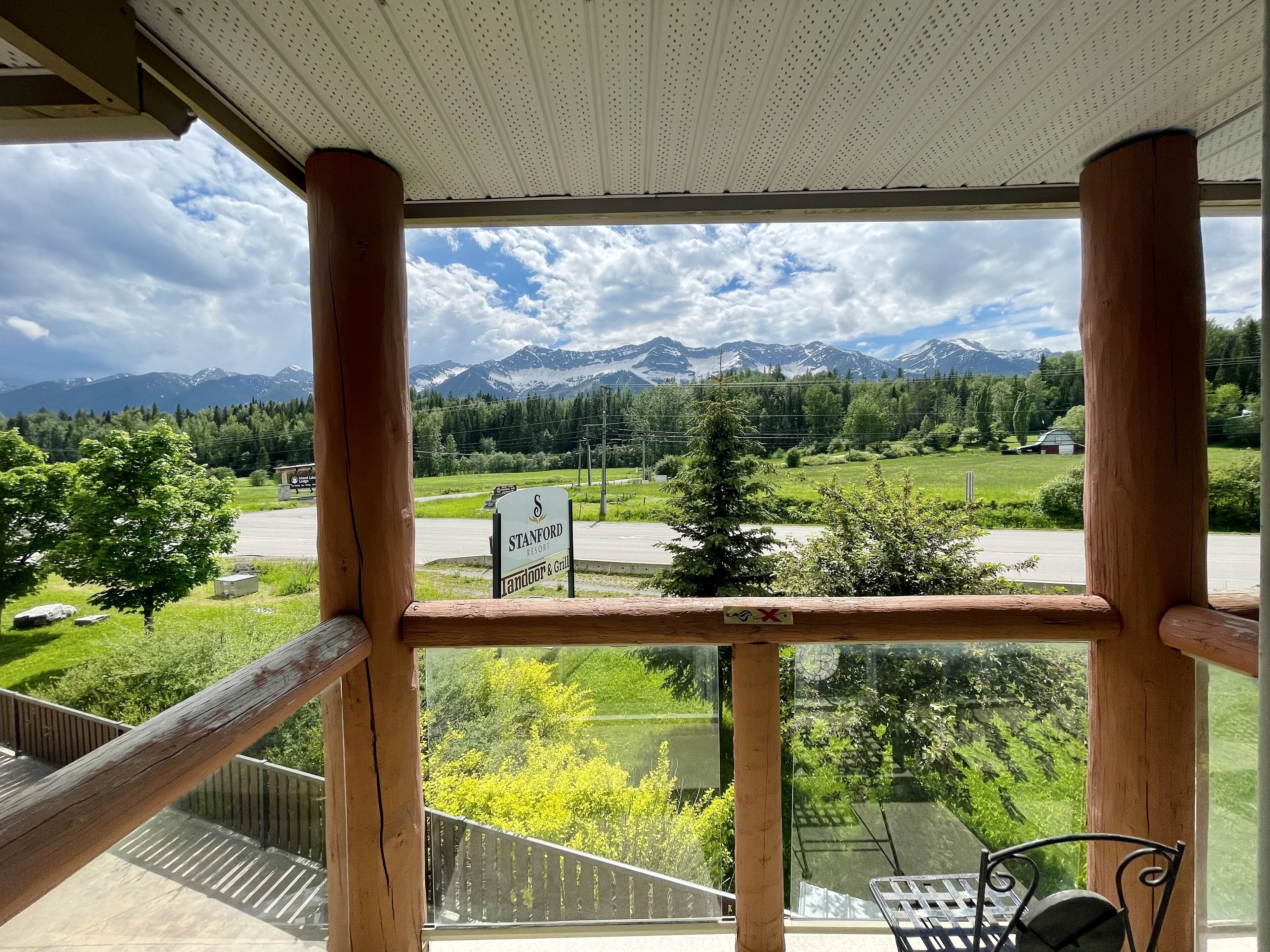 A wooden balcony with a view of mountains, a road, and a sign for Stanford Resort & Grill.