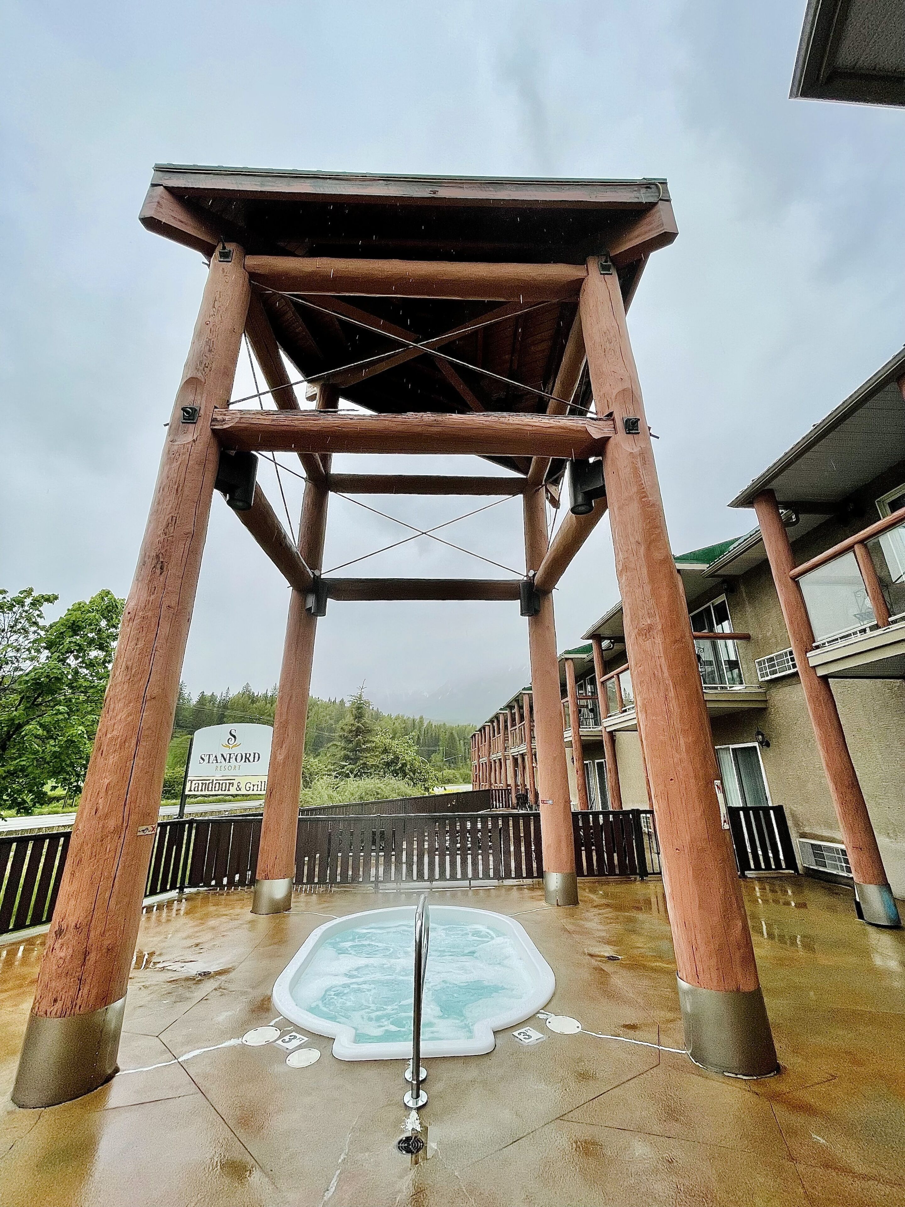 A wooden pergola structure with a hot tub underneath.