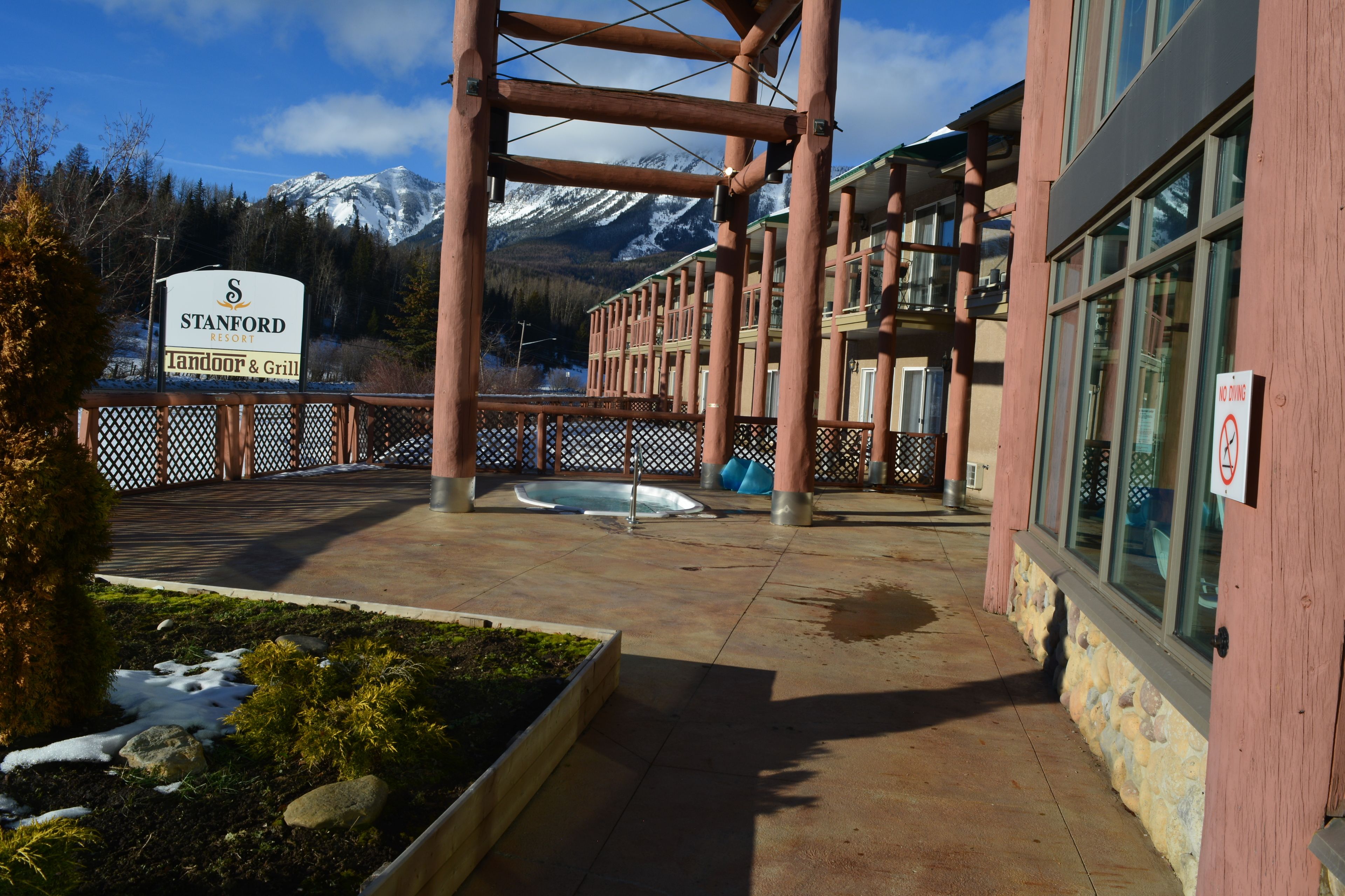 A resort with a sign for 'Stanford Resort Landoor & Grill', a hot tub, and a view of snow-capped mountains.