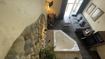 A modern living room with a stone accent wall, a large bathtub, and a gray sofa.