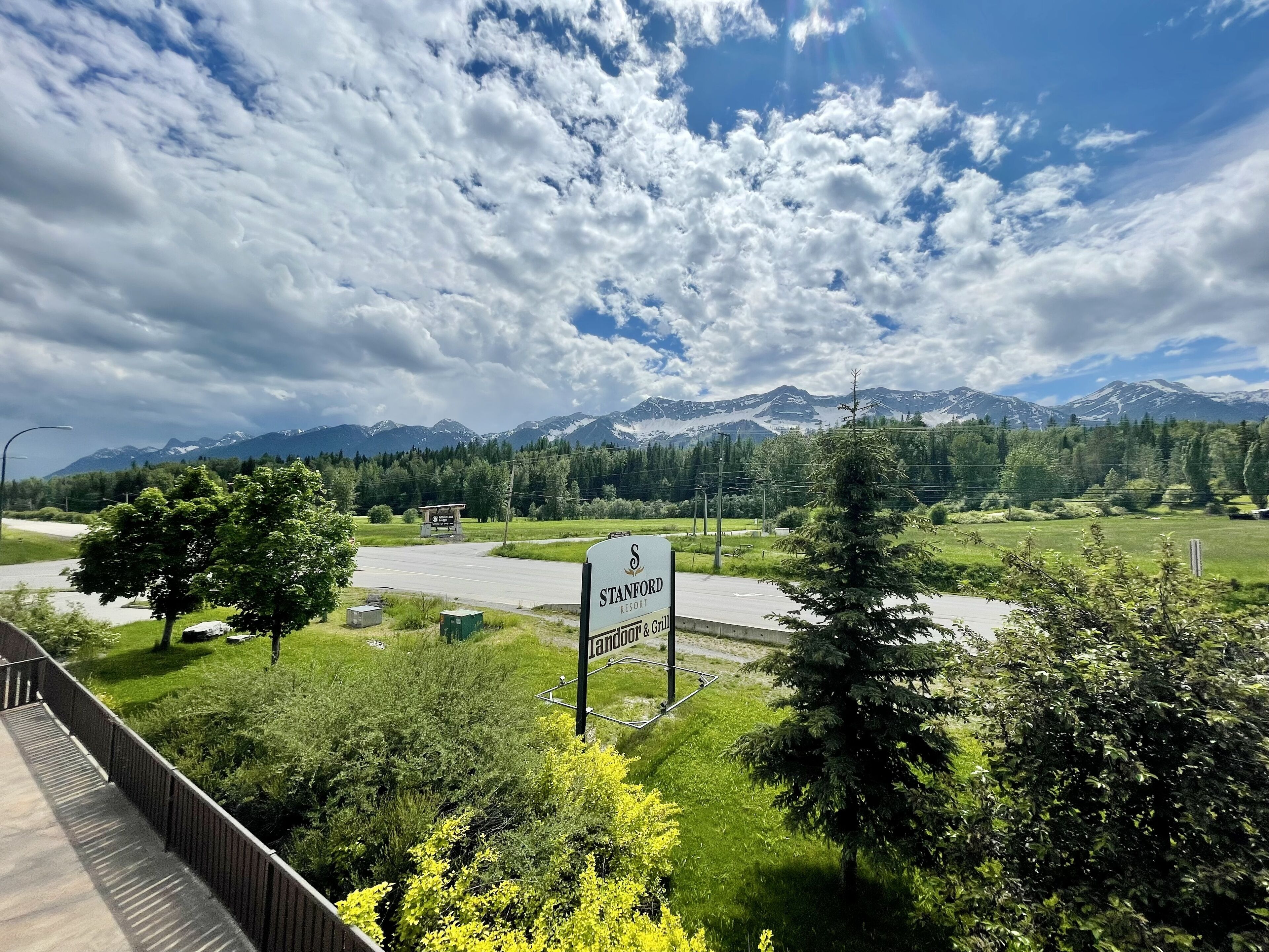 A sign for the Stanford Resort with a view of mountains and a road.