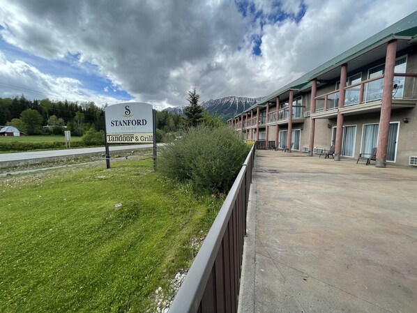 Señal de Stanford Resort, con cocina tandoor y parrilla, un edificio con balcones y mesas al aire libre.