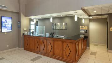 A reception area with a wooden counter, a digital display, and a modern light fixture.