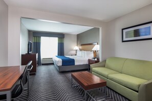A hotel room with a bed, a green sofa, a desk with a chair, a TV, and a framed picture on the wall. - Best Western Inn & Suites San Mateo - San Francisco Airport (San Mateo)