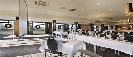 A spacious conference room with long tables, chairs, and a chandelier.