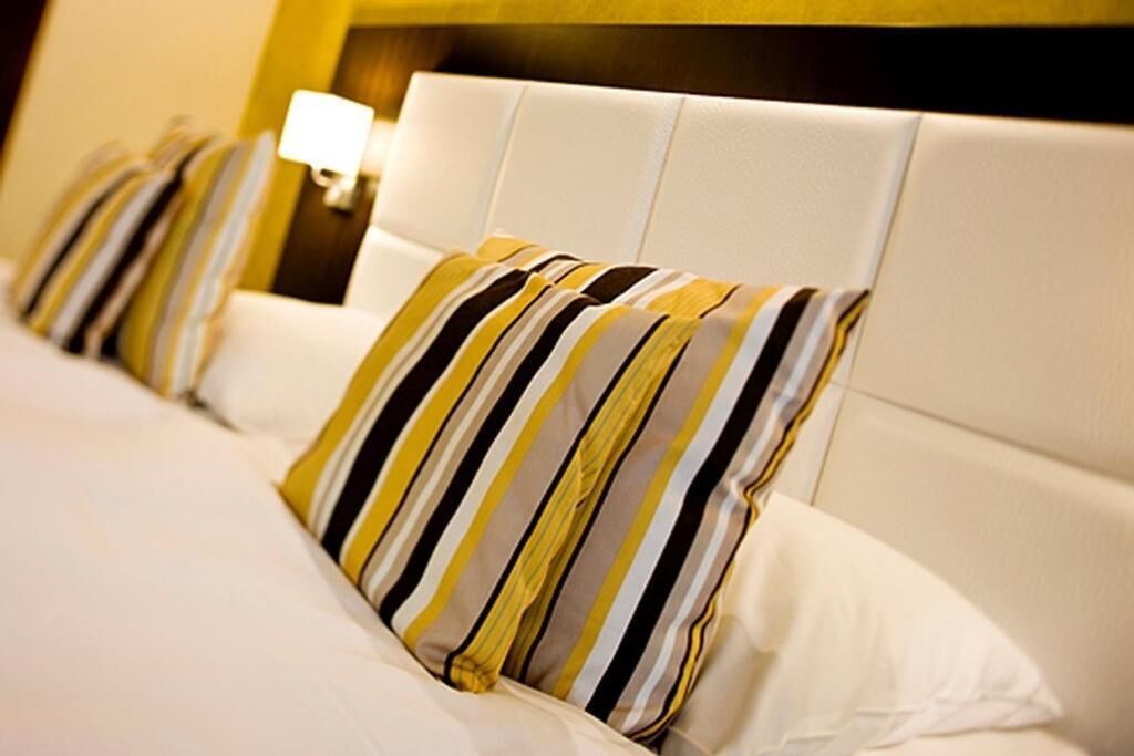 A hotel room with a white headboard and striped pillows.