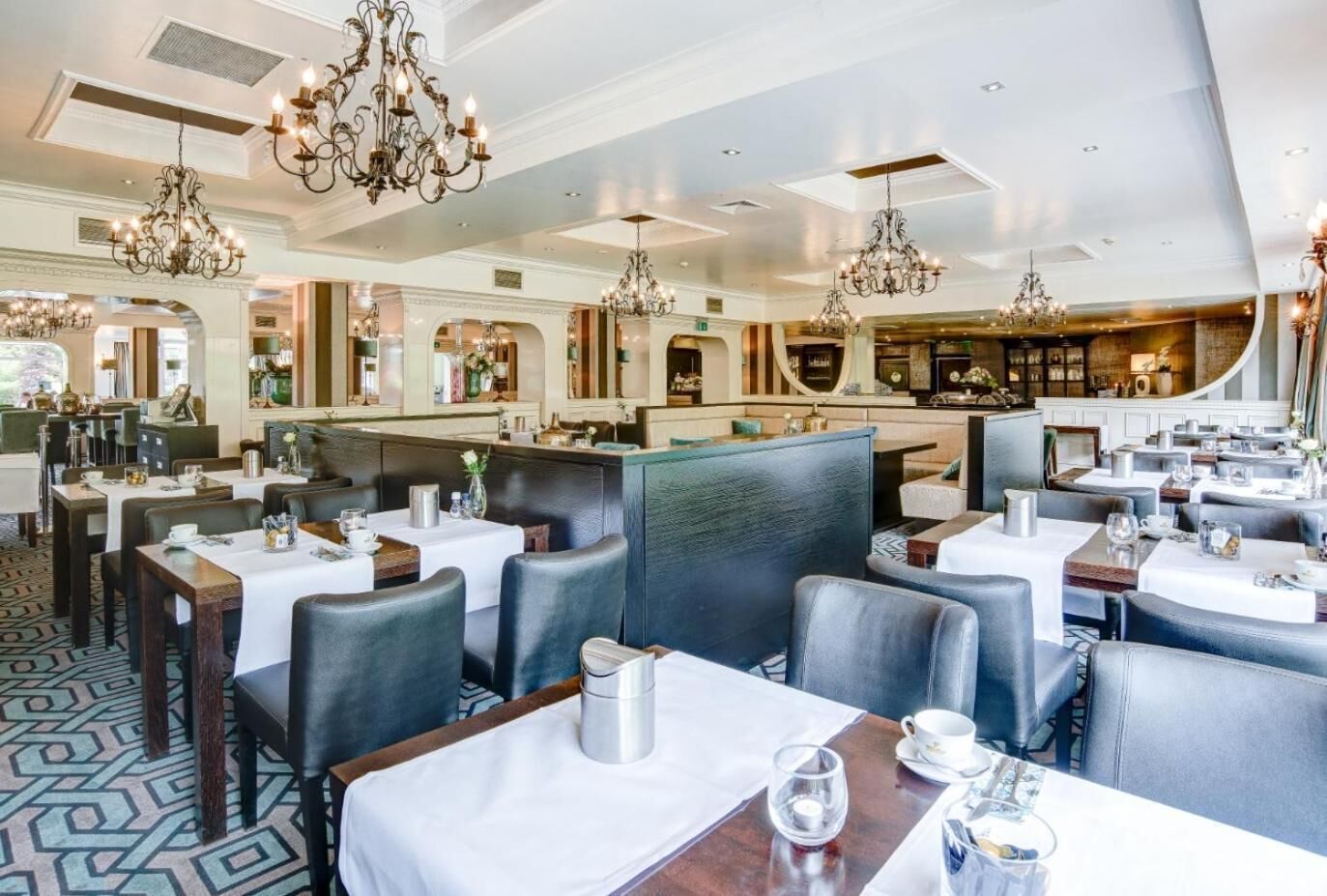 Een restaurant met verschillende eetgedeeltes, elk met tafels en stoelen, en weelderige kroonluchters.