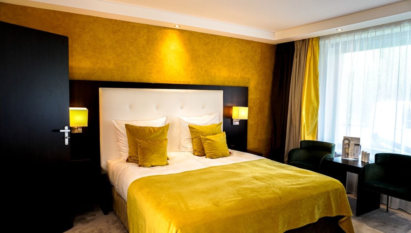 A hotel room with a large bed, two bedside tables, a chair, and a window with curtains.