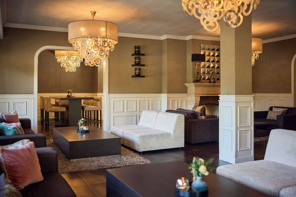A spacious living area with modern furniture, a fireplace, and decorative lighting fixtures. - Van der Valk Hotel Moers (Moers)