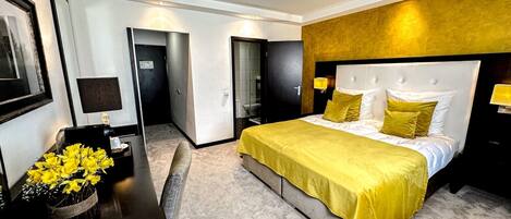 Una habitación de hotel moderna con una cama grande, una mesita de noche y un espejo.