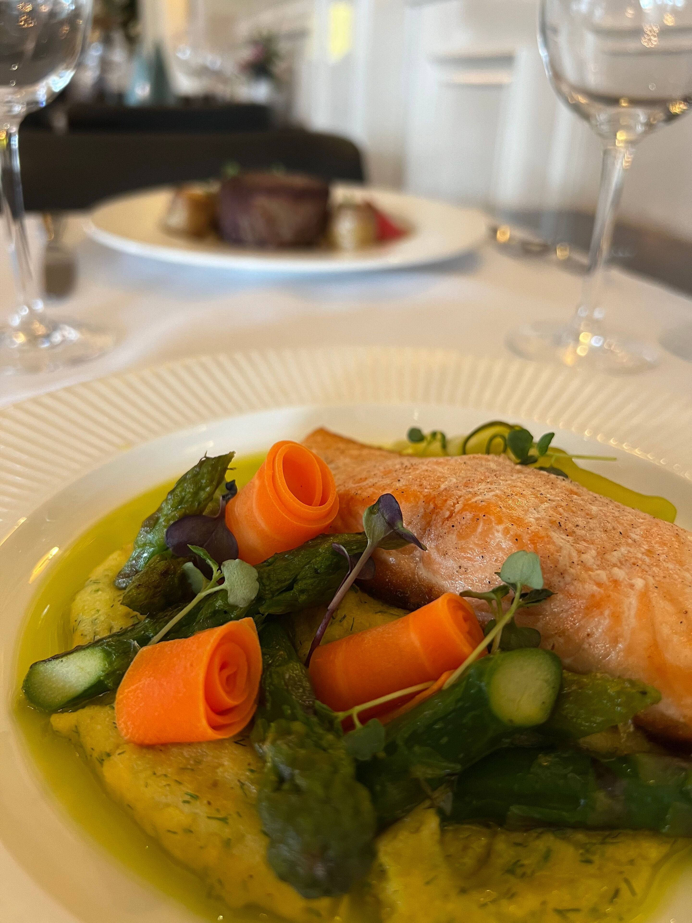 A plate of food with a salmon fillet, asparagus, and a yellow sauce.