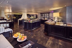 A spacious hotel lobby with a central island featuring a buffet, surrounded by seating areas and a large chandelier. - Van der Valk Hotel Moers (Moers)