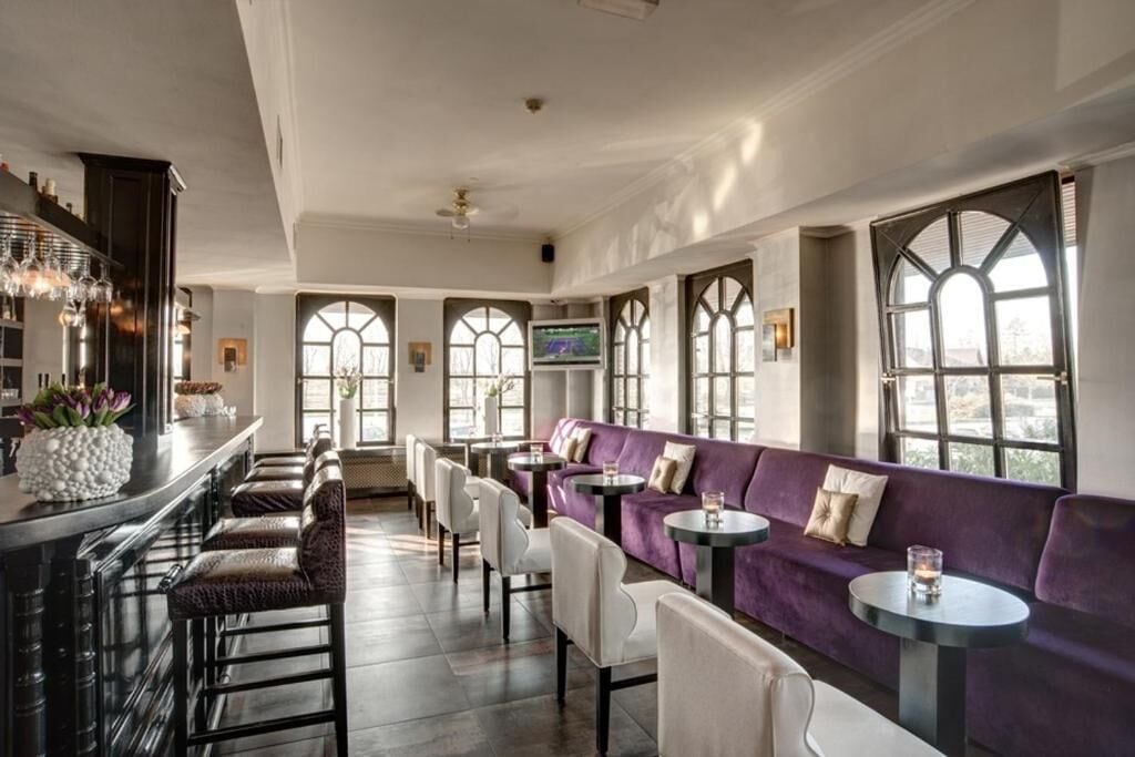 Een ruime zithoek met een bar, zitgedeeltes en grote ramen die voor natuurlijk licht zorgen.
