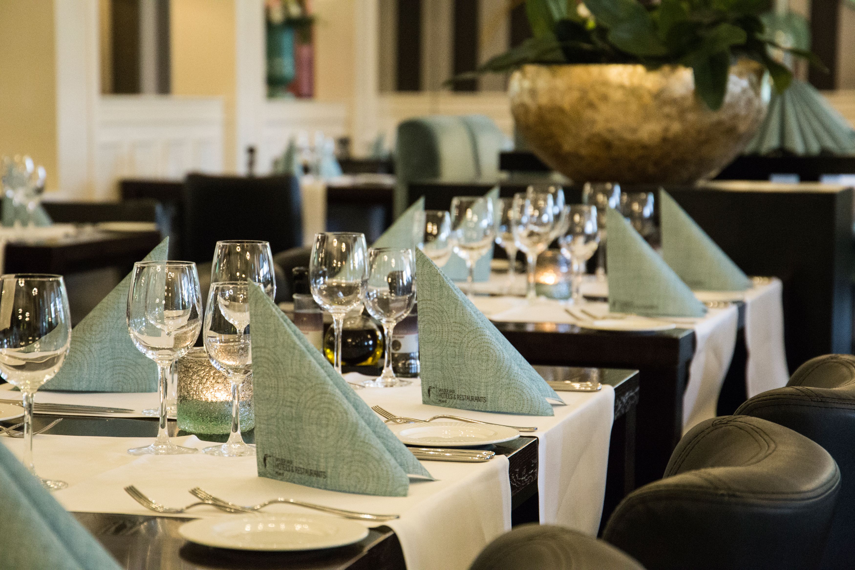 Un restaurante con mesas dispuestas para comer, incluyendo copas de vino, platos y cubiertos.
