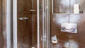 A modern bathroom with a glass-enclosed shower, a white toilet, and a marble-tiled wall.