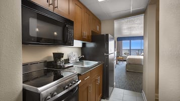 Cocina compacta con estufa, microondas y refrigerador, que da a un balcón con vistas.