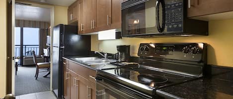 Una cocina moderna con electrodomésticos de acero inoxidable, armarios de madera y un amplio ventanal con vistas a un balcón.