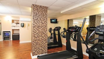 Une salle de sport équipée de tapis de course, dotée d’un mur avec des miroirs et d’un mur décoratif en briques.