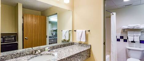 A bathroom with a granite countertop sink, a large mirror, and a shower area.