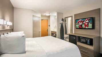 A hotel room with a bed, a television, a microwave, and a small kitchenette.
