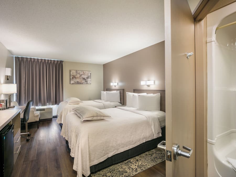 Habitació d'hotel amb llit, taules de nit, escriptori i cadira, televisió i un bany amb banyera.