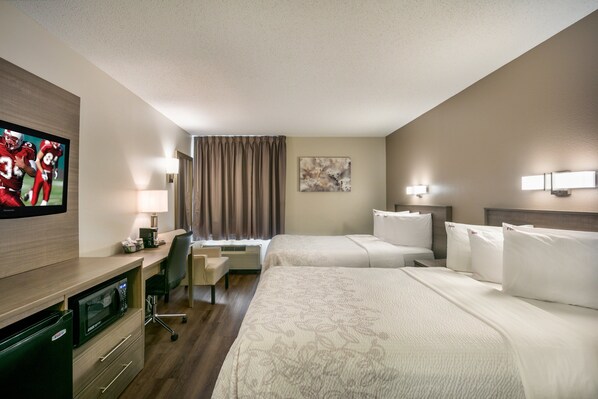 A hotel room with two beds, a desk with a computer, a television, and a microwave. - Red Roof Inn PLUS+ Boston - Logan (Saugus)