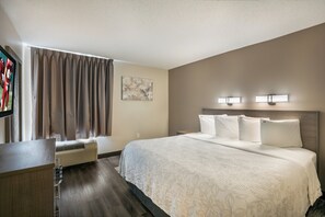 A hotel room with a bed, a desk, a TV, and a window with curtains. - Red Roof Inn PLUS+ Boston - Logan (Saugus)
