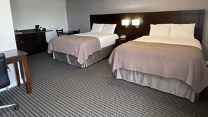 Habitación de hotel con dos camas, un escritorio y una silla.