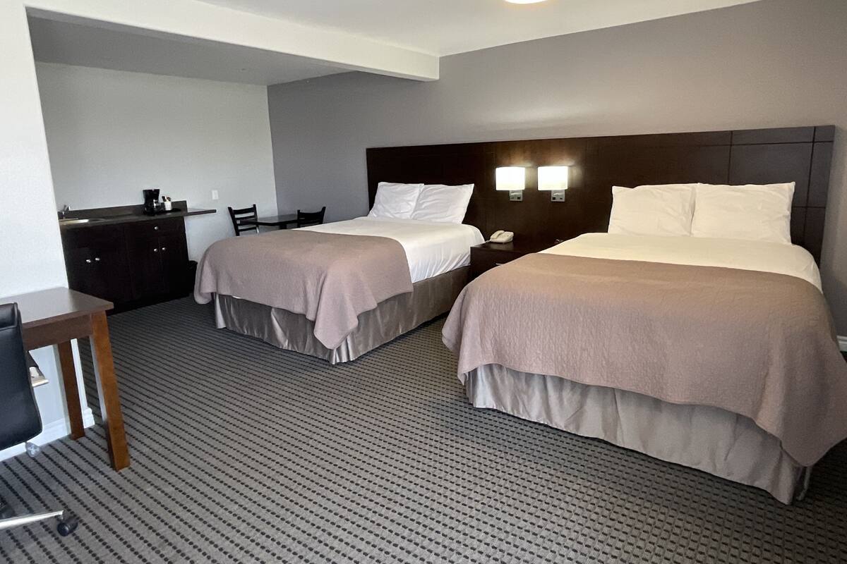 Quarto de hotel com duas camas, uma escrivaninha e uma cadeira.