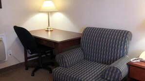 Una habitación de hotel con un escritorio, una silla, una lámpara y un teléfono.